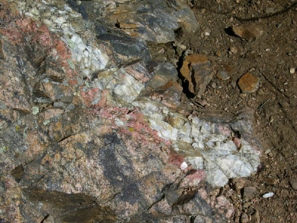 Pegmatitic intrusion of milky or white quartz and feldspar along the Chimney Gulch Trail